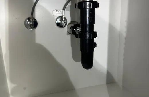 Newly fitted P-trap and supply lines under a kitchen sink cabinet