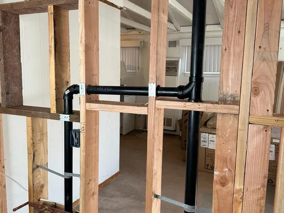 A new black drain stack and branch lines installed in an open framed wall